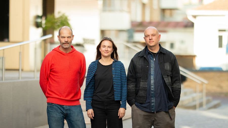 Three Harvest Moon team members standing outdoors against a blurred urban background