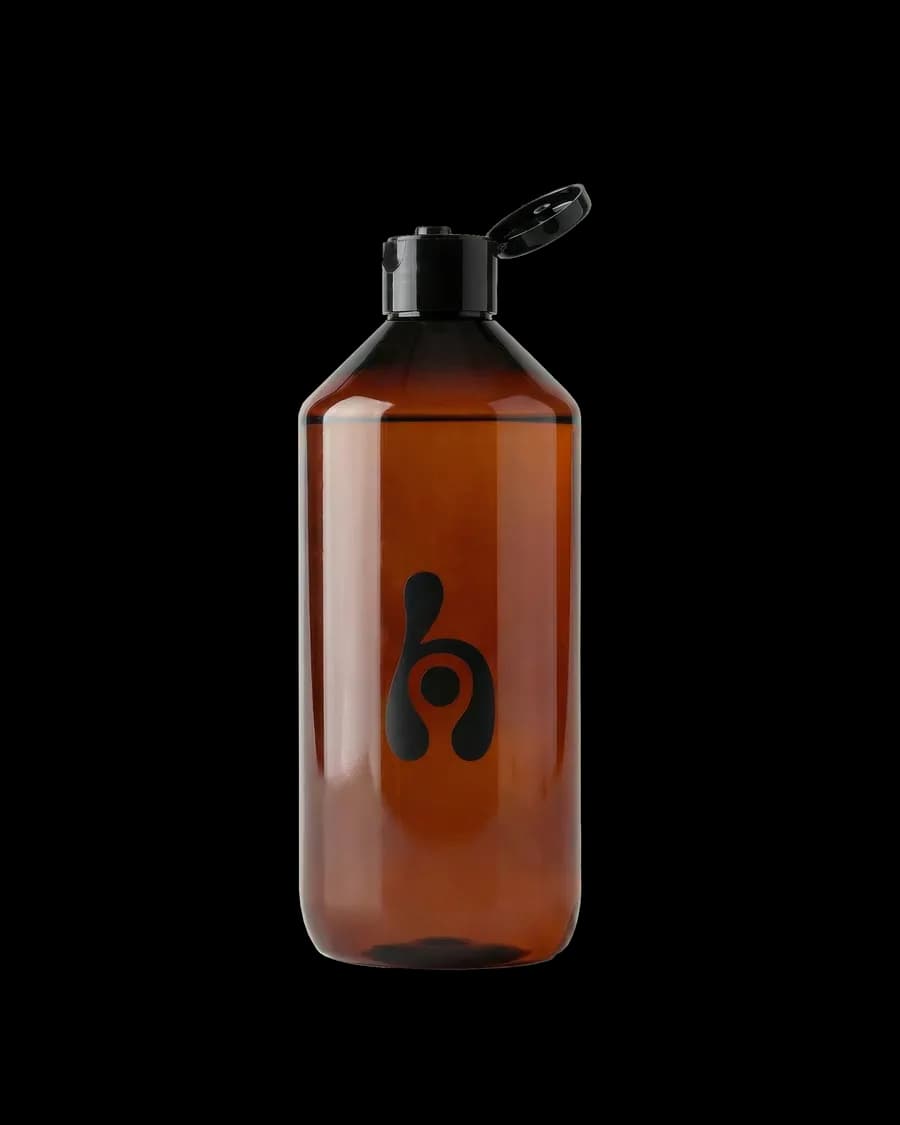 Genomskinlig brun Afterflush-flaska, 1 liter, med öppet svart lock och Harvest Moon-logotyp